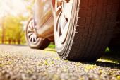 Car tires closeup on asphalt road on summer day at park